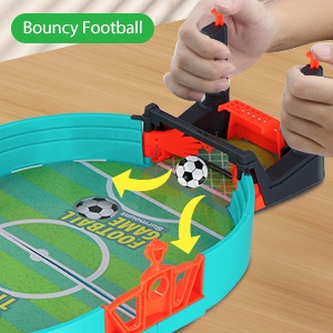 Jeu de football de table avec joueurs en plastique, poteaux de but et ballon rebondissant. Mains visibles des figurines manipulant les joueurs.