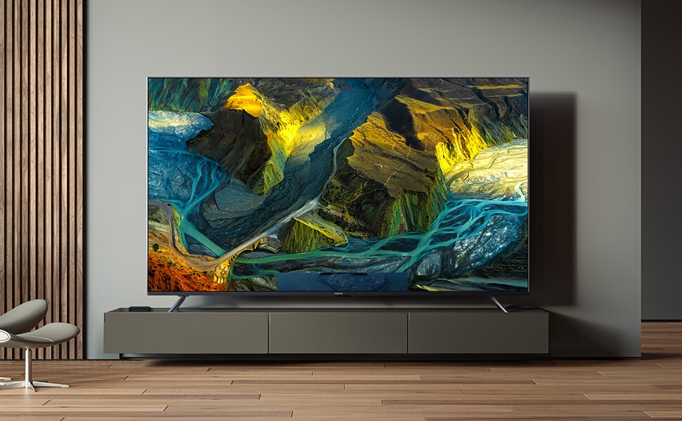 Grand téléviseur à écran plat accroché au mur, affichant une peinture abstraite vibrante avec des tourbillons bleus, jaunes et verts. Le téléviseur se trouve au-dessus d'une élégante unité de divertissement.